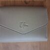 Close-up of embossed Elion logo on beige vegan leather wallet with contrast stitching