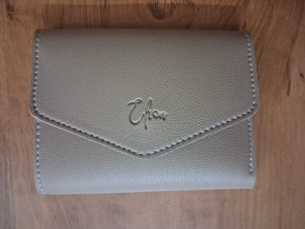 Close-up of embossed Elion logo on beige vegan leather wallet with contrast stitching